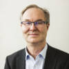 Jyri Seppälä katsoo kameraan, silmälasit ja puku.