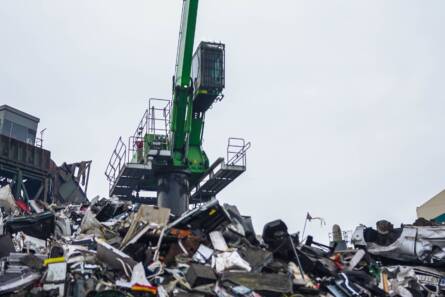 Kuvassa Kajaanin Romu -yrityksen sähköllä toimiva materiaalinkäsittelykone ulkotiloissa metalliromuröykkiön päällä. Suurikokoisella koneella lajitellaan ja käsitellään metalliromua.
